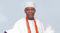 Ọba Ghandi Olaoye wọ agbádá funfun, mú ìrùkẹ̀rẹ̀ lọ́wọ́