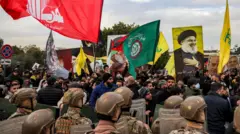 متظاهرون يلوحون بأعلام حركتي حزب الله وأمل اللبنانيتين وصورة حسن نصر الله أمام جنود في الجيش اللبناني خلال تجمع لإغلاق طريق مؤد إلى مطار بيروت الدولي في بيروت.