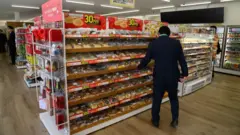 Muškarac u prodavnici pod rafa sa robom