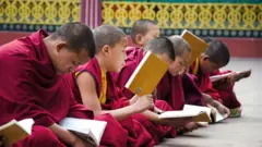 Meninos tibetanos estudando sentados no chão