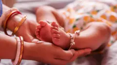 በሴት እጅ የተያዘ የህጻን ልጅ እግር