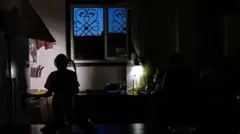 زنی در حال آماده‌سازی غذا در هنگام قطع برق در دورود، ایران، در تاریخ ۱۱ مه ۲۰۲۵
