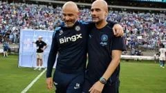 Image of Enzo Maresca, manager of Chelsea, and Pep Guardiola, manager of Man City embracing on di pitch.