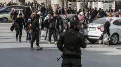 یک نیروهای امنیتی، هم‌زمان با فرار ساکنان از محله کردنشین «اشرفیه» حلب، در حال نگهبانی است