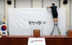 지난 2020년 3월 당명을 '미래통합당'에서 '국민의힘'으로 변경한 국민의힘 담당자가 서울 여의도 국회 당대표회의실의 백드롭 교체 작업을 하고 있다. 배경에는 '국민의 힘으로'라는 글씨가 보인다.