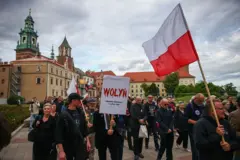 Люди йдуть з прапорами Польщі, на транспаранті на передньому плані написано "Wołyń", літери написані червоним, і з них стікає кров