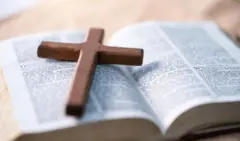 Cross dey on top Bible.