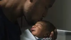 Umugabo uteruye umwana w'uruhinja