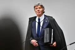 Fux de toga, com pastas embaixo do braço, em pé em sala do STF e com olhar confiante