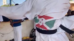 Umugabo wazamuye umugeri wambaye umwenda wera uriho ibendera ry'u Burundi