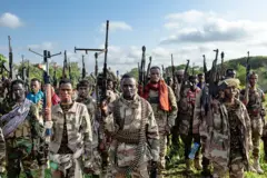 Un grupo de soldados somalíes de pie con sus armas apuntando al cielo.