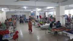 In a hospital room, parents or relatives are sitting and sleeping with the beds lined up on both sides