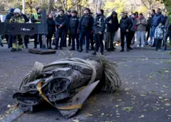 Pessoas observam os restos de um míssil hipersônico russo Zircon abatido, após atingir um prédio residencial em Kiev em novembro de 2024