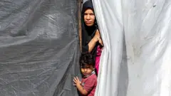 Una mujer y un niño miram desde una tienda de campaña en Gaza.