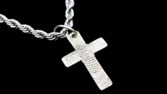 Cruz de prata presa a uma corrente prateada sobre fundo preto