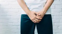 man wearing shorts holding genitals