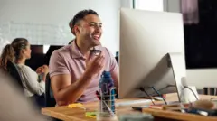 Funcionário sorrindo em frente ao computador no escritório