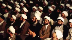 Reunião de homens sentados com roupas tradicionais xiitas