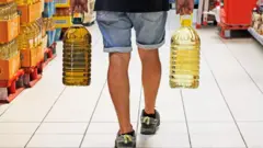 شخص يحمل زجاجتين من زيت بذور