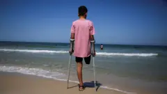 Photo d'un garçon palestinien qui a perdu sa jambe lors d'un raid israélien, debout devant la plage de Gaza (septembre 2024).