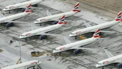 Vista aérea de um grupo de aviões da British Airways estacionados em fileiras, com as aeronaves próximas entre si e equipamentos de serviço ao redor