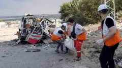 Paramedics carry a body bag from a destroyed ambulance, 11 October