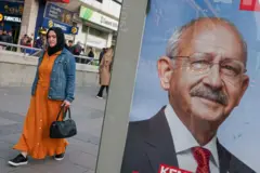 Kılıçdaroğlu posterinin önünde yürüyen bir kadın. 