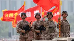 北京天安門城樓前戰旗方隊裝甲車上的四名中國解放軍士兵向天安門城樓上的習近平敬禮（3/9/2025）