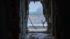 Um prédio visto através do buraco aparentemente causado por uma explosão.