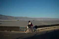 Migrante passando de bicicleta pelas estufas de Almeria