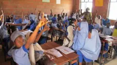 Awọn akẹkọọ to wọ aṣọ alawọ aro, wa ninu yaara ikẹkọọ wọn pẹlu olukọ to n kọ wọn