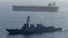 Bir savaş gemisi ve tanker suda görünüyor. 