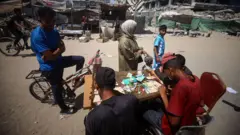 Un grupo de gente repara sus billetes en una mesa ubicada en la calle en Gaza.