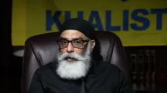 لمبی سفید داڑھی اور چشمہ لگائے ایک شخص، جو ٹائی اور بٹن والی قمیض پہنے ہوئے ہے، ایک ایسے جھنڈے کے سامنے کھڑا ہے جس پر ’خالصتان‘ لکھا ہے