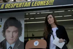 Villarruel segurando um papel. Atrás há uma foto de Javier Milei