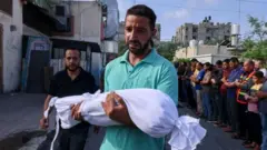 Homem carrega corpojogo de ganhar dinheiro na horacriança morta no conflito entre Israel e Hamas