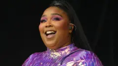 Cantora Lizzo sorrindo em show