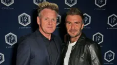 غوردون رامزي يرتدي بدلة زرقاء داكنة وقميصاً أسود، وديفيد بيكهام يرتدي سترة سوداء وقميصاً أبيض.