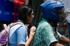 এক স্কুল শিক্ষার্থীর হাতে ব্যাটারিচালিত ছোট ফ্যান।