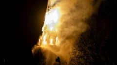 Kilisenin kulesi alevler içinde, bir itfaiye eri gece karanlığında su sıkıyor.