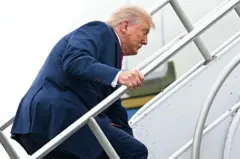 Le président américain Donald Trump trébuche alors qu'il monte à bord d'Air Force One avant son départ de l'aéroport municipal de Morristown, dans le New Jersey, le 8 juin 2025, en route pour Camp David.