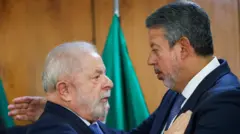 Lula e Lira se cumprimentando com abraços em sala 