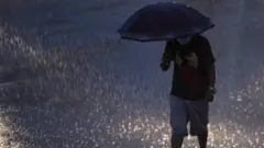 वर्षा हुँदा छाता ओढेका एक व्यक्तिको साङ्केतिक तस्बिर