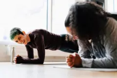 Duas mulheres rindo fazendo prancha