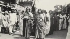 अस्थायी राष्ट्रीय ध्वज पकड़े हुए बहिष्कार जुलूस का नेतृत्व करती महिलाएं