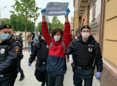 Jovem segura um cartaz enquanto a polícia o escolta