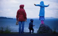 Mãe com dois filhos junto ao mar