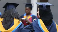 تصویر دو زن جوان که عبا و کلاه فراغت از دانشگاه به تن دارند. یک زن دیگر نیز در پس زمینه عکس دیده می شود که لباس مشابه آن‌ها را پوشیده است. 