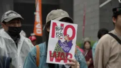 デモ参加者らが、NO WAR（戦争反対）と書かれたプラカードを顔の前に掲げるなどしている