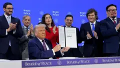 Prezydent USA Donald Trump prezentuje swój podpis na akcie założycielskim Rady Pokoju.
